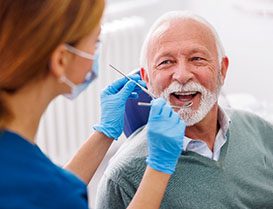 Senior man smiling at Arlington Heights dentist during checkup