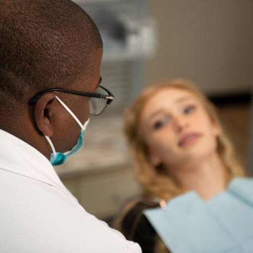 Young blonde woman in dental chair talking to her dentist