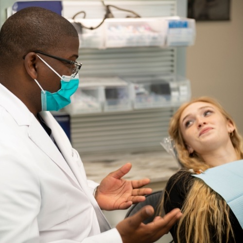 Dentist talking to young blonde woman in dental chair