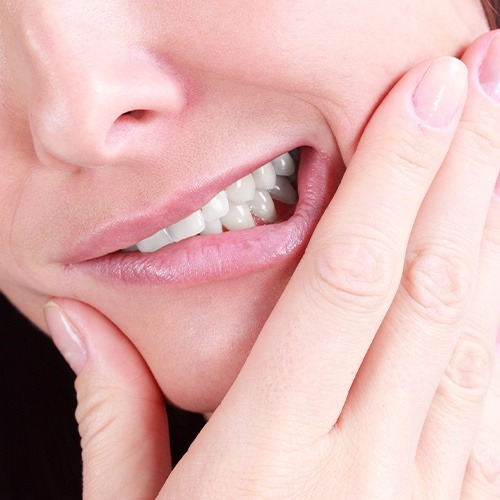 Person holding their cheek in pain before root canal treatment