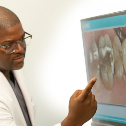 Dentist pointing to photo of damaged tooth