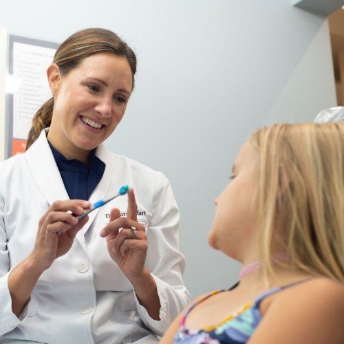 Dentist showing a toothbrush to a child patient