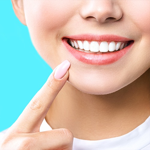 Person pointing to their smile after teeth whitening in Arlington Heights