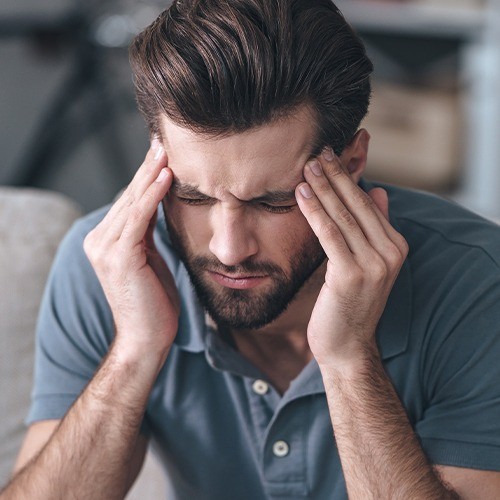 Man in need of T M J therapy holding head in pain