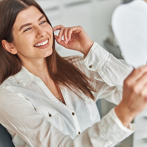 Young woman at the dentist’s office smiling in the mirror
