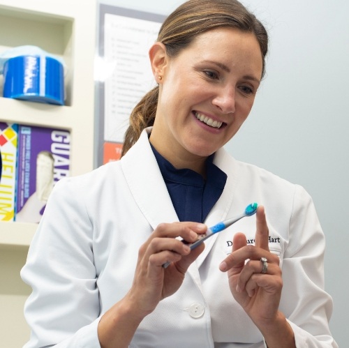 Woman brushing teeth after porcelain veneer placement