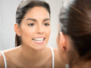 woman looking at her new porcelain veneer in mirror