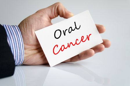 Someone holding a card that reads, "Oral Cancer"