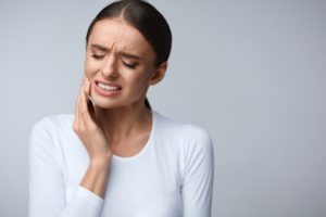 Woman in white shirt with tooth pain