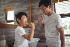 Father and son brushing teeth together