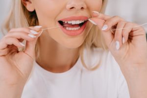 Close up of blonde woman using flossing tips 