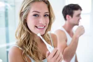 Woman brushing her teeth using tips from safe dentist 