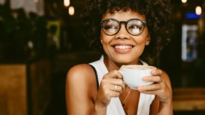 Woman smiling with coffee after brushing teeth before breakfast