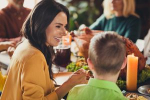 Woman with dentures smiling at the thanksgiving table 