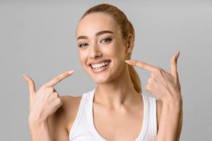 Woman smiling while pointing to her teeth