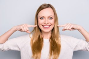 Woman smiling enthusiastically while pointing to her smile
