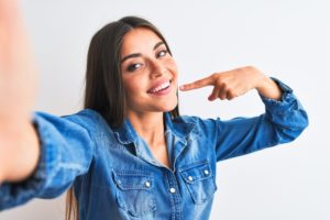 Woman smiling pointing to her smile while taking a selfie