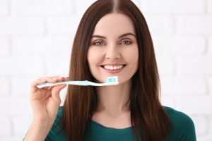 Woman with brown hair brushing her teeth