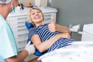 Woman smiling in dental chair with thumbs up