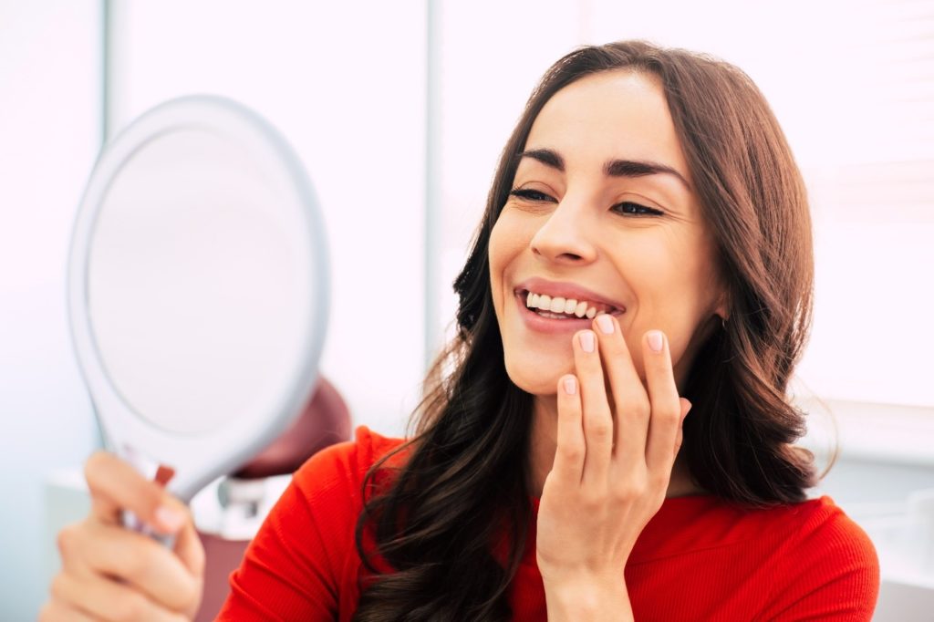 Closeup of woman smiling at reflection in mirror