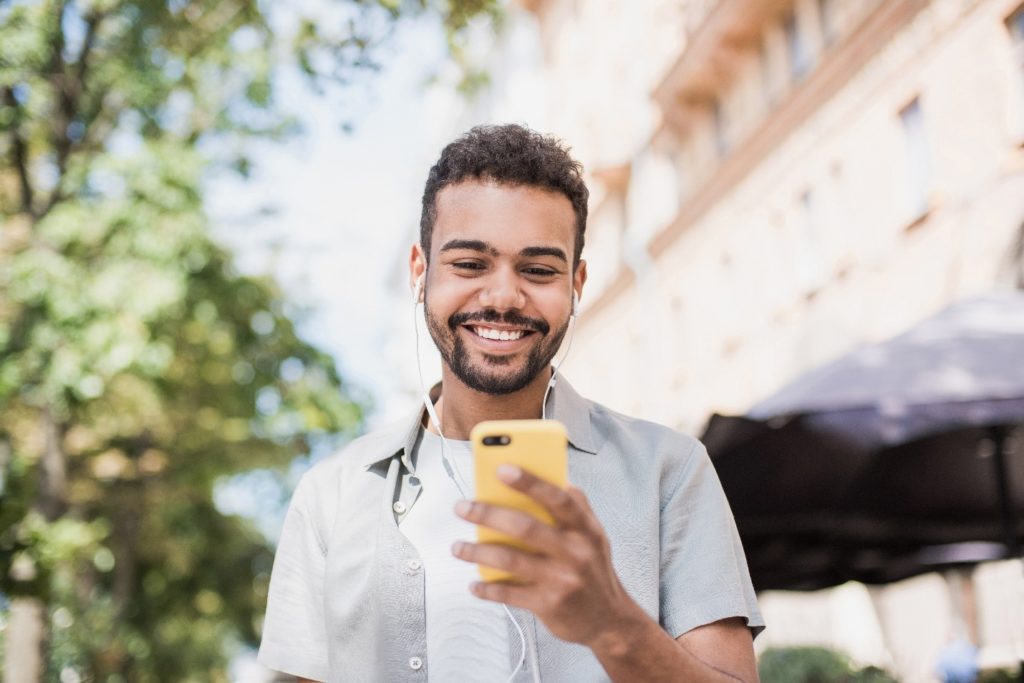 Man smiling on phone while walking around outside