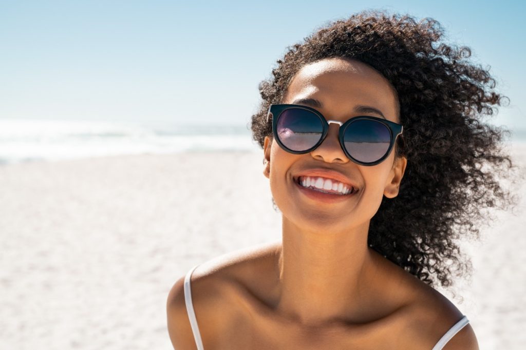 Woman in sunglasses smiling on beach