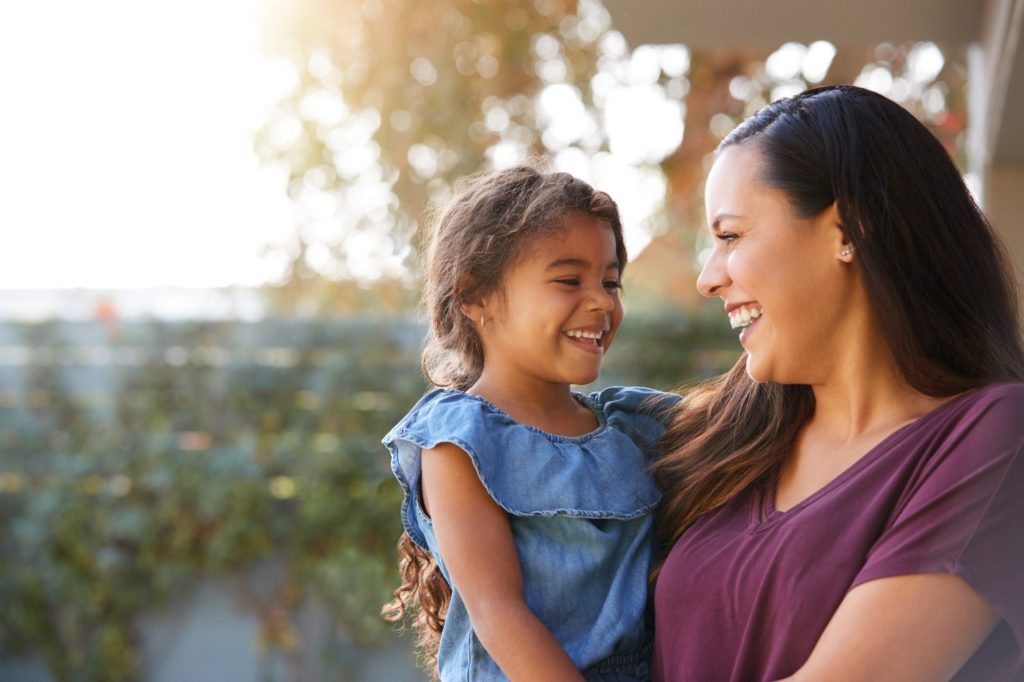 Mom and daughter smiling at each other outside