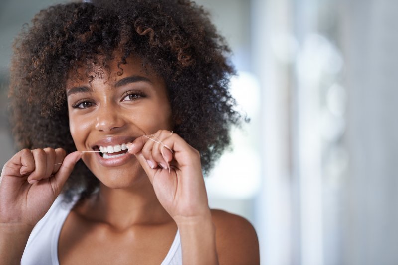 close up of young woman flossing teeth in bathroom