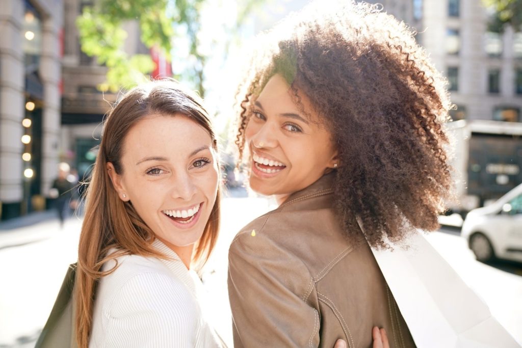 Friends smiling while shopping outside