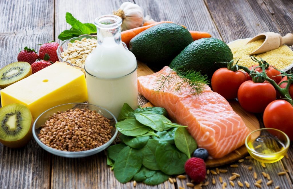 Salmon, vegetables, and fruits lying on wooden table