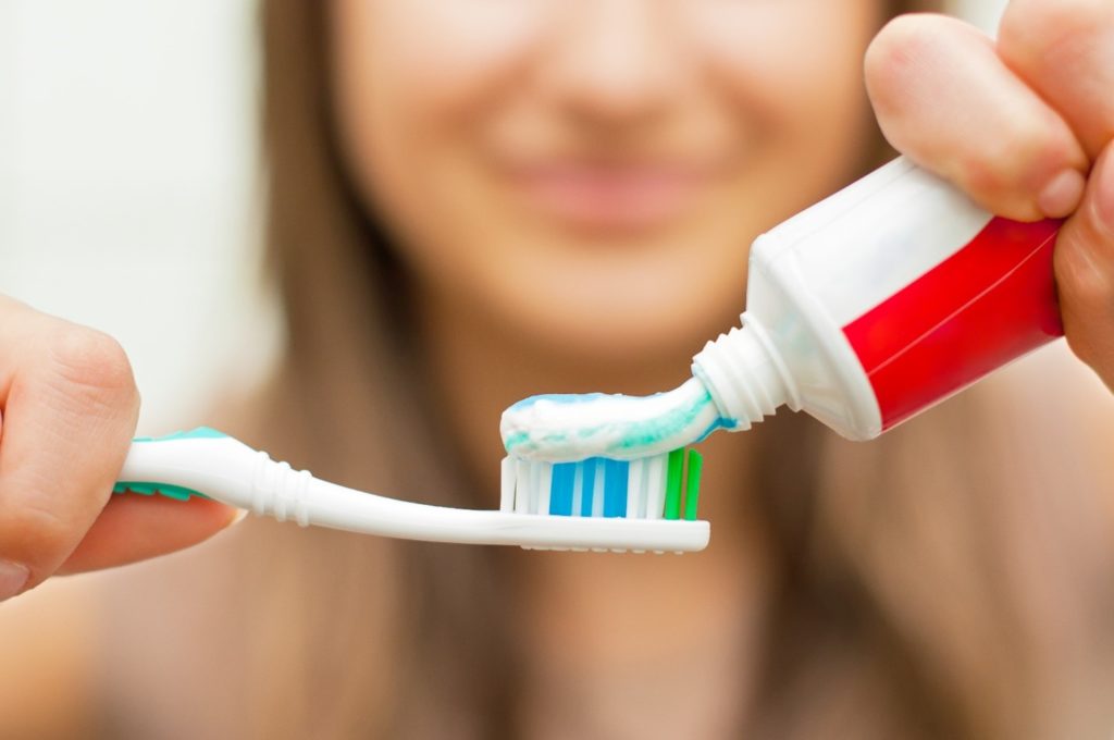 Woman applying desensitizing toothpaste to toothbrush