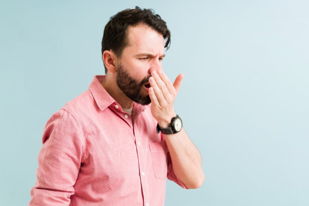 Man in pink shirt checking if his breath smells