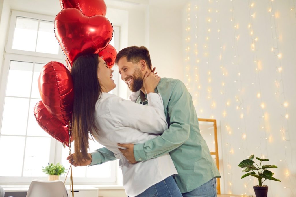 Happy couple dancing around balloons on Valentine's Day