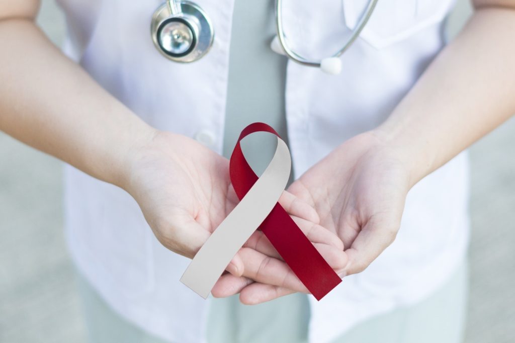 Doctor holding red and white ribbon for oral cancer awareness