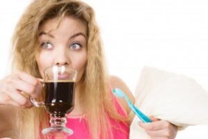 woman drinking coffee and holding a toothbrush