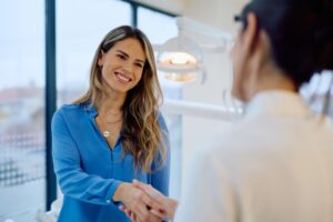 female patient smiling and shaking hands with the dentist